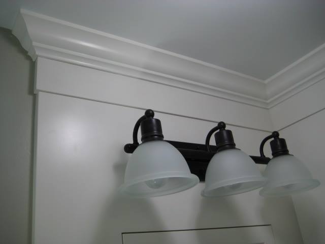 Painted crown molding and panel above this vanity are nicely accented by the oil rubbed bronze light fixture.
