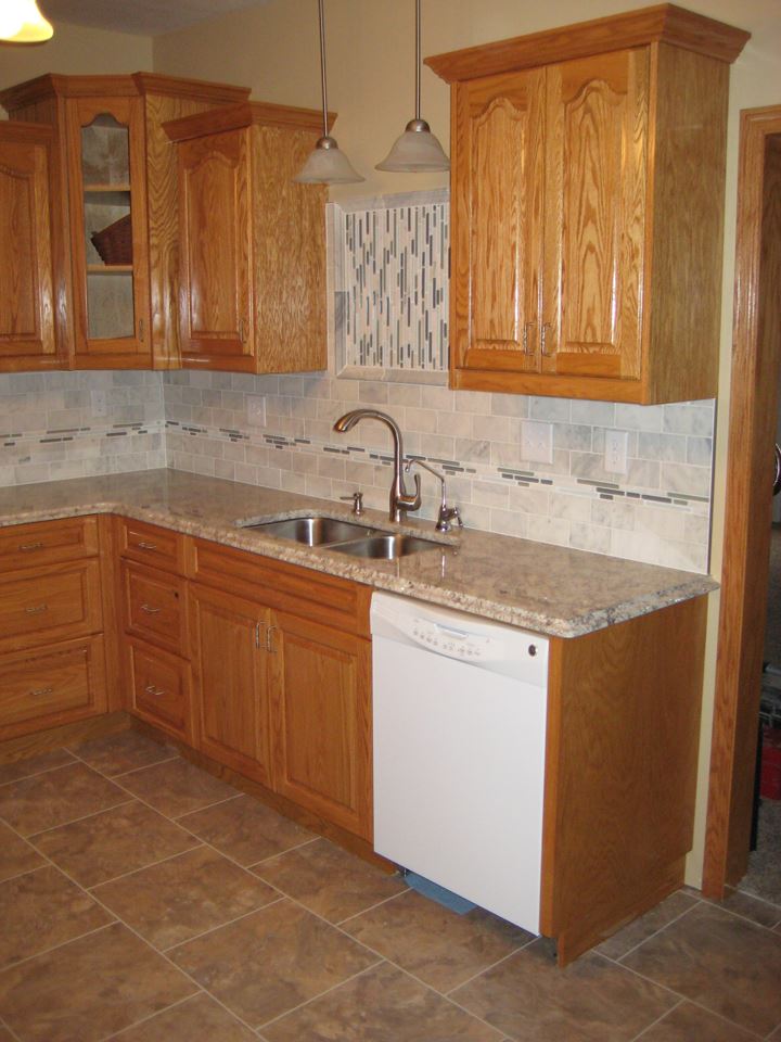 Red oak kitchen cabinets with marble tile backsplash.